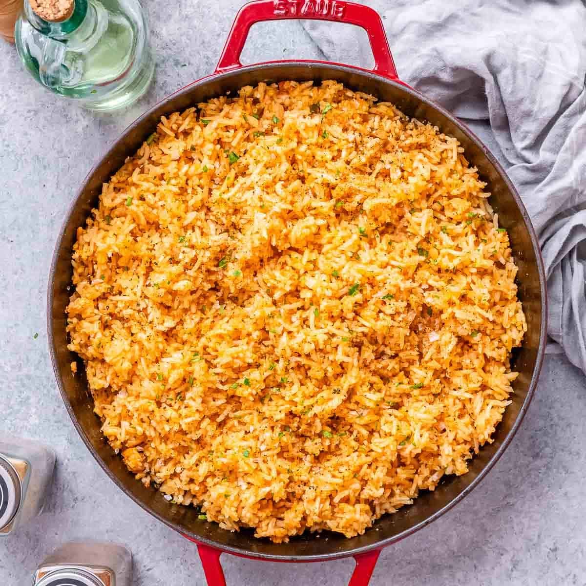 Prato colorido com arroz mexicano ao lado de quinoa, arroz integral e couve‑flor, acompanhado de peito de frango grelhado
