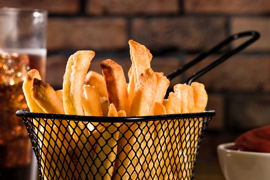 Porção de batatas fritas douradas ao lado de uma balança de precisão e uma fita métrica sobre mesa de madeira