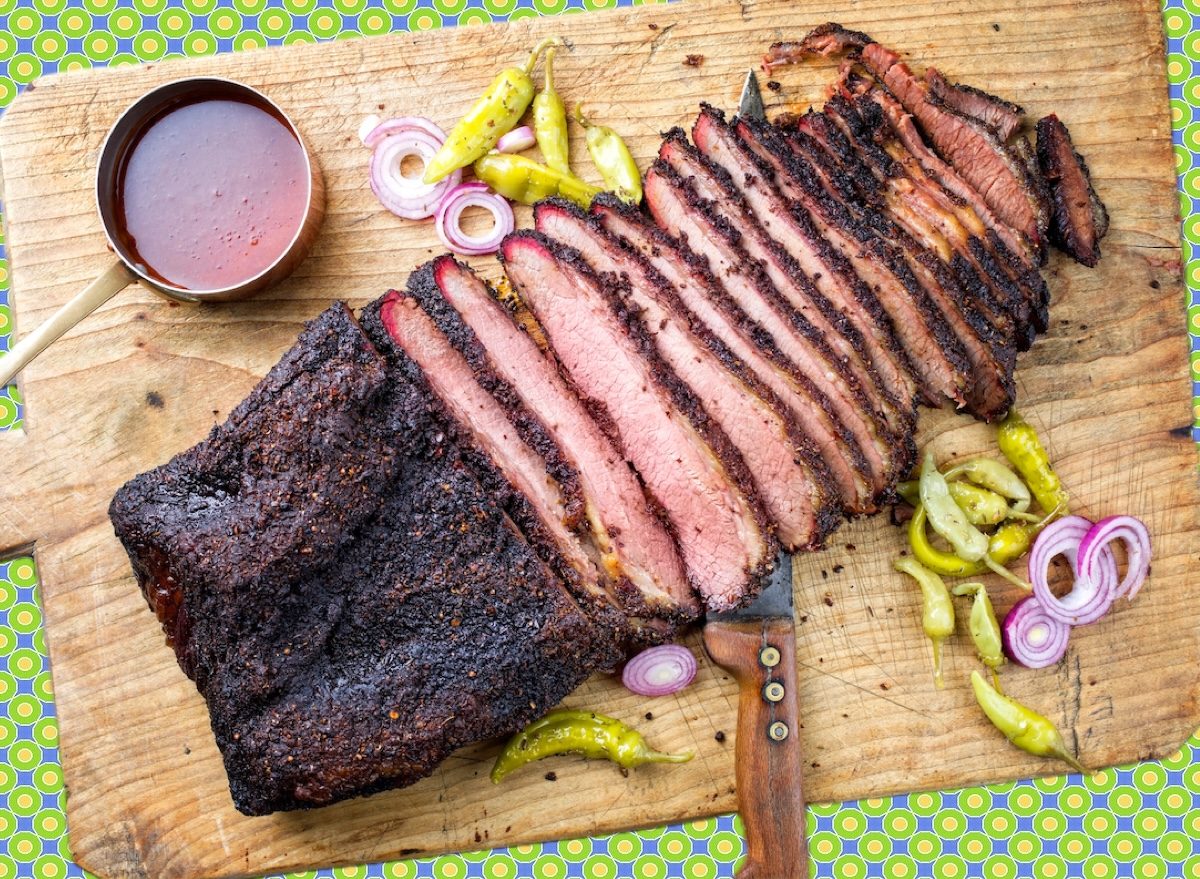 Fatias de brisket grelhado ao lado de salada verde com tomate, abacate e quinoa, formando um prato balanceado