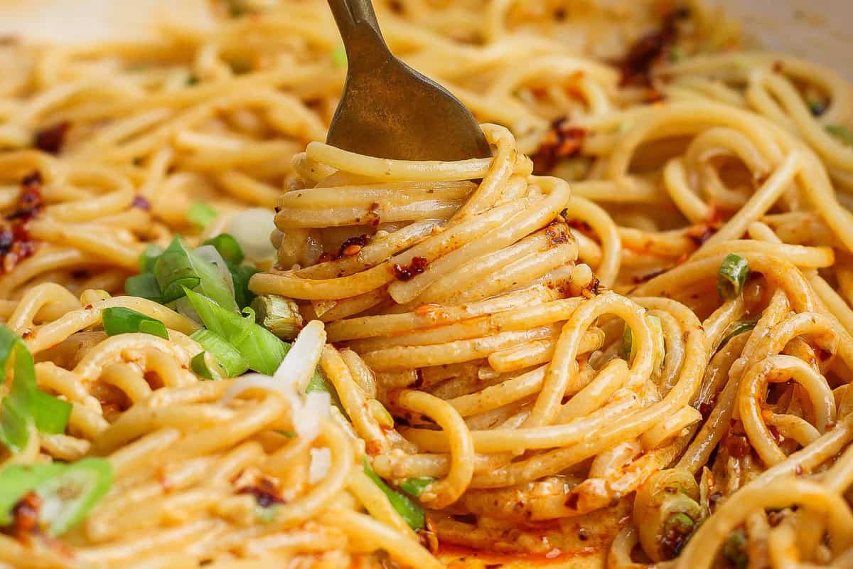 Pessoas preparando receitas saudáveis em cozinha com chili crunch em pratos e garrafas de azeite extra-virgem