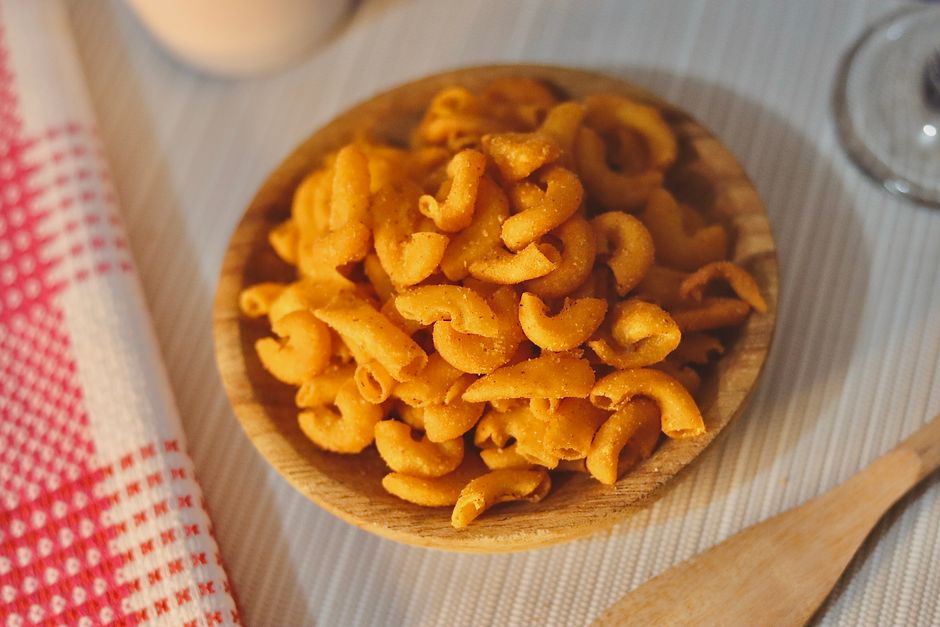 Um prato de macarrão cremoso coberto com chili picante e queijo derretido em uma tigela de cerâmica