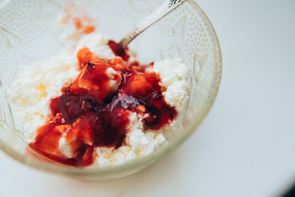 Um prato de cottage cheese branco fresco, com fatias de frutas e nozes, sobre uma toalha de mesa de cor pastel