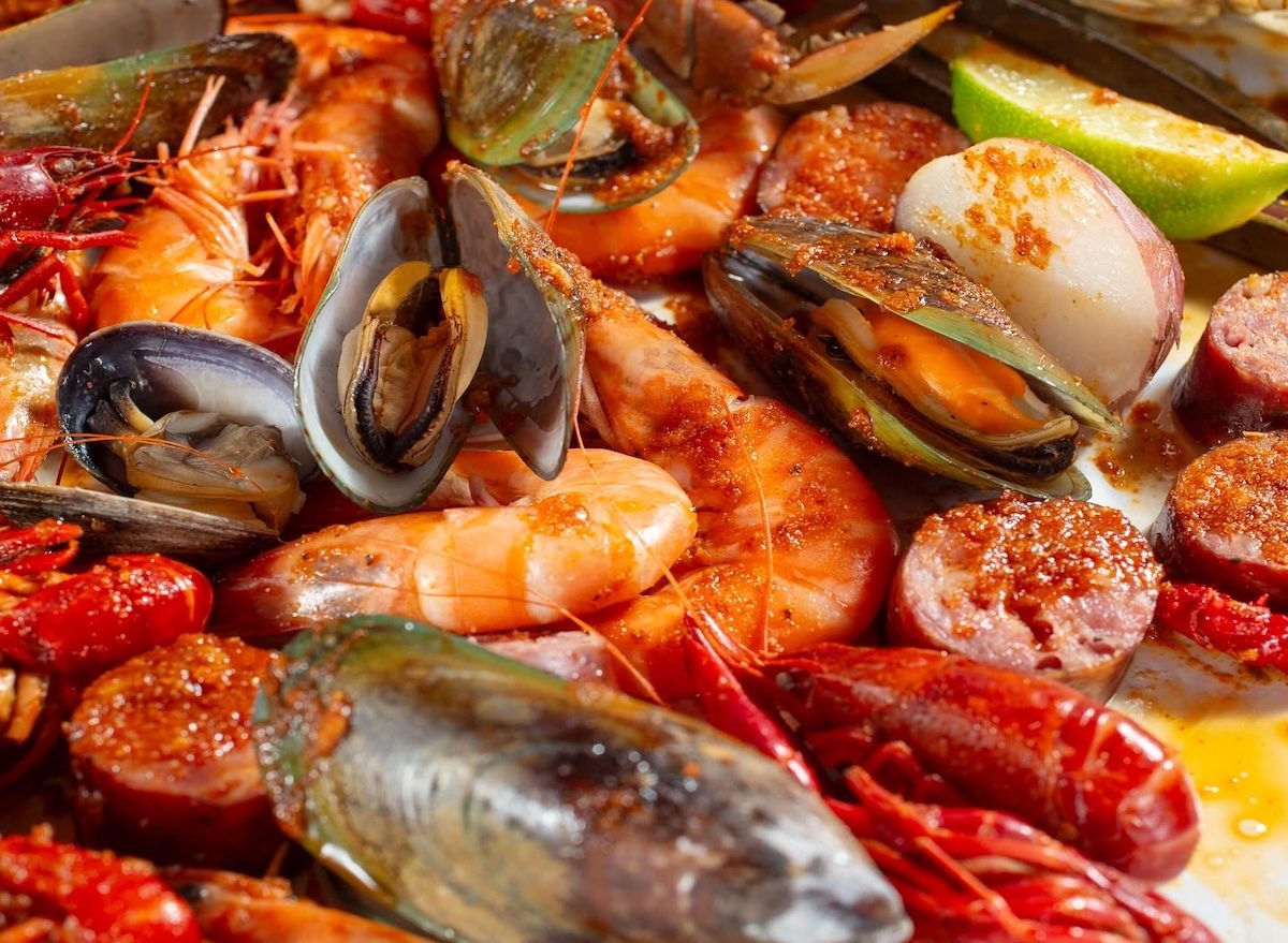 Um prato quente de crawfish com molho de limão e alho, acompanhado de frutas frescas e folhas de couve