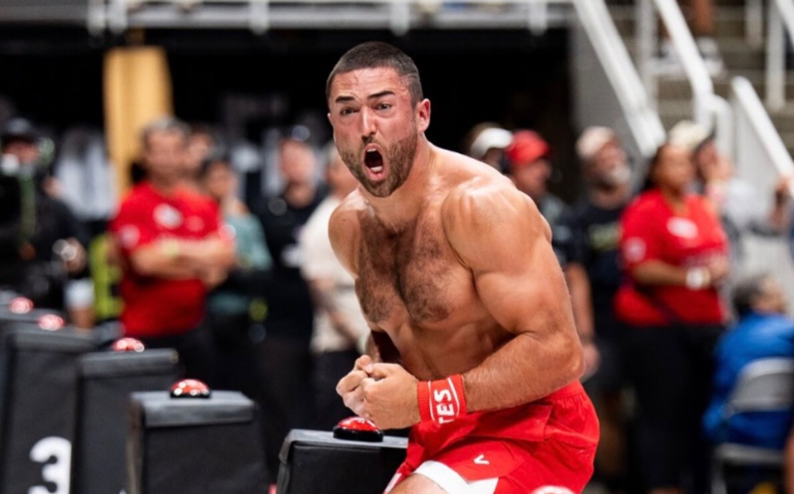 Um atleta masculino em movimento de "burpee" com pesado barra de peso ao fundo