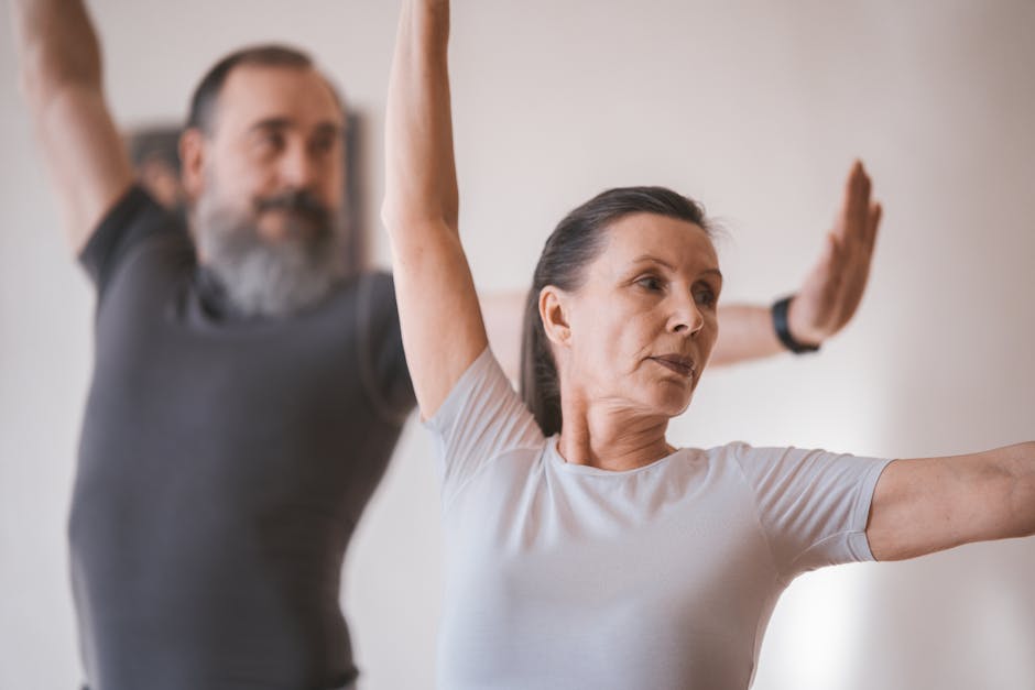 Idosa sorridente pratica agachamento com apoio em uma cadeira de madeira em uma sala iluminada e bem arejada