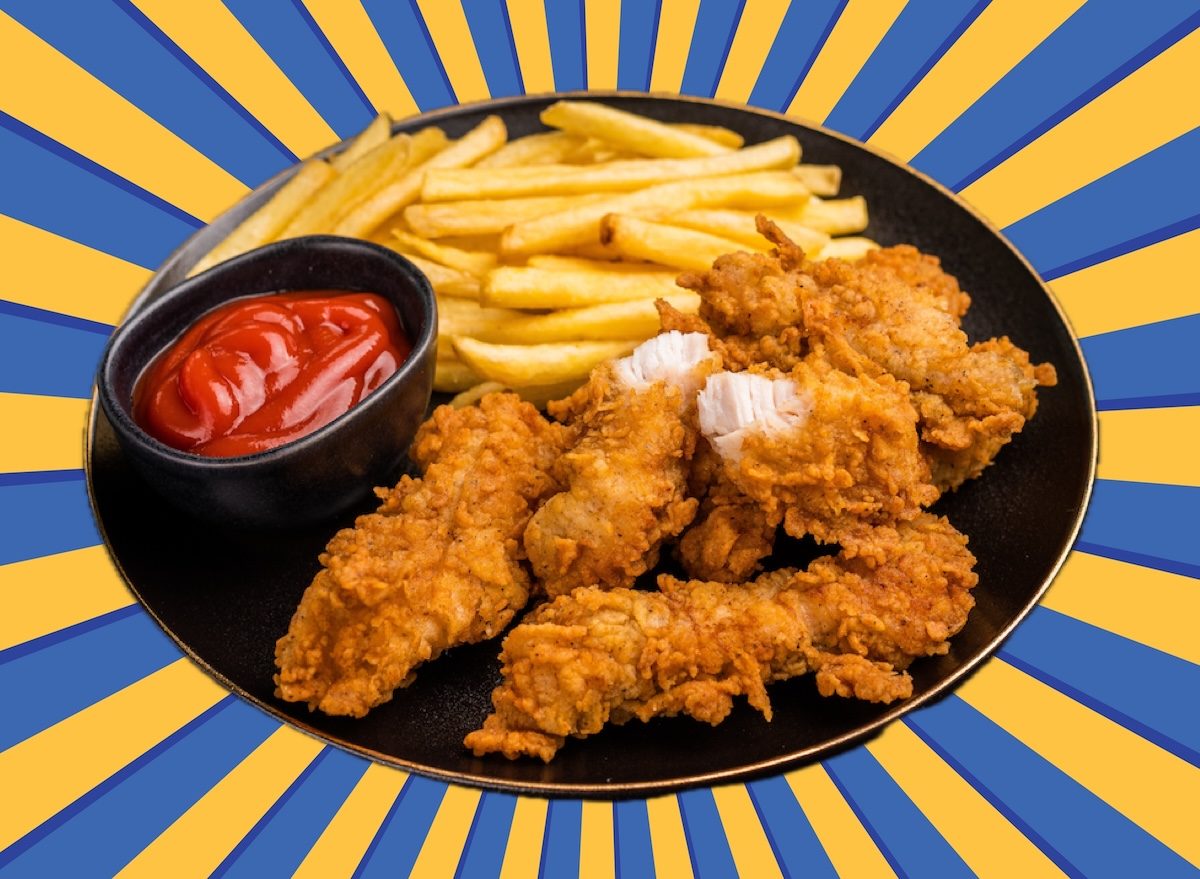 Frango frito dourado ao lado de batatas rústicas assadas, com folhas de rúcula e um limão cortado ao meio
