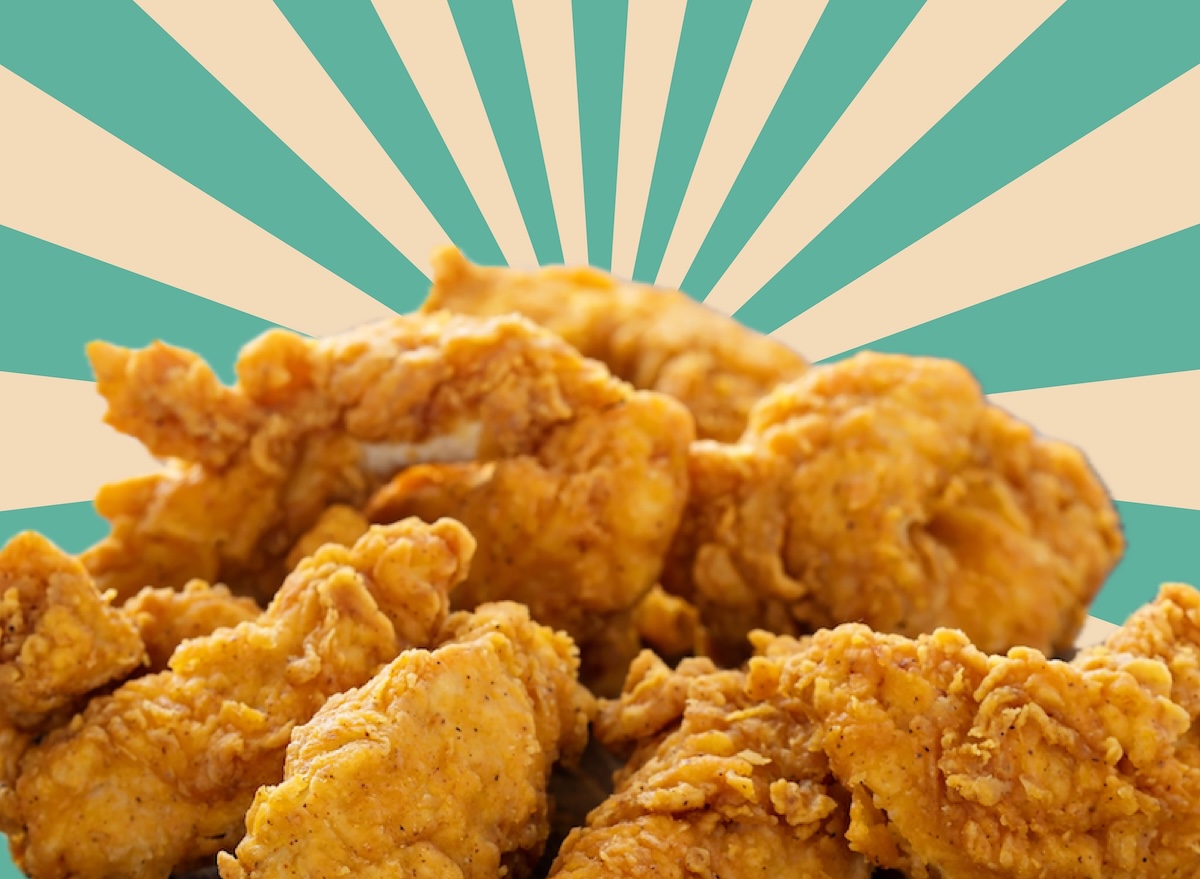 Pedaços de frango frito dourado ao lado de halteres e uma fita métrica sobre uma mesa de madeira rústica