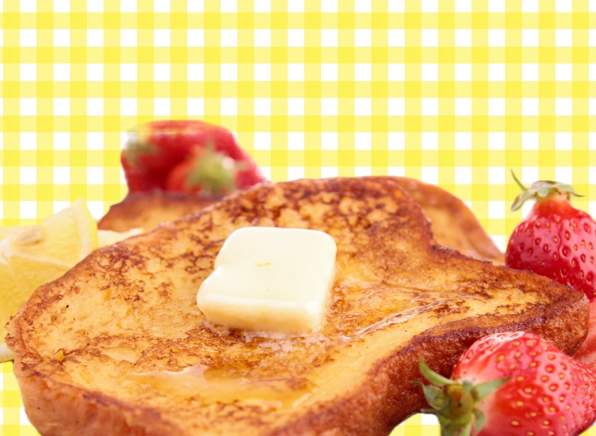 Prato com French toast dourado, coberto por morangos, mirtilos e amêndoas, ao lado de um copo de suco verde