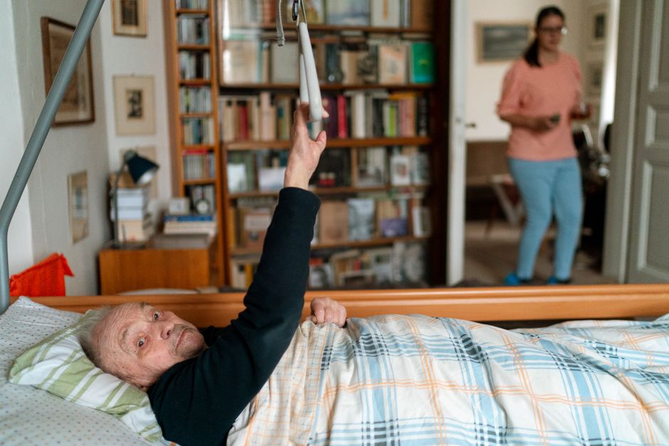 Uma mulher em pé, com um peso leve nos quadris e um braço estendido para cima, realizando um exercício de hip abduction
