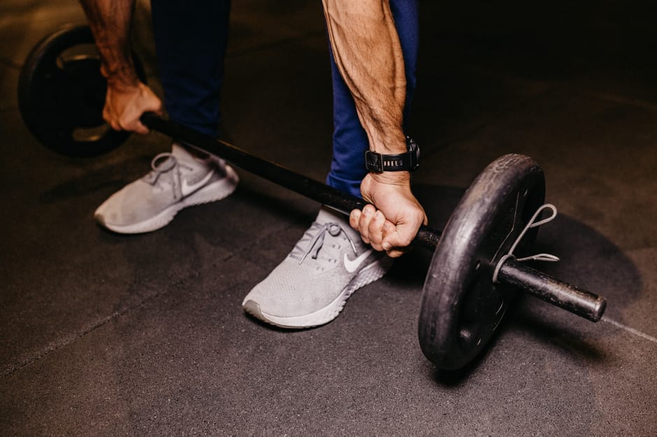 Atleta realizando elevação de panturrilha em pé na máquina com foco na contração muscular e calçado esportivo