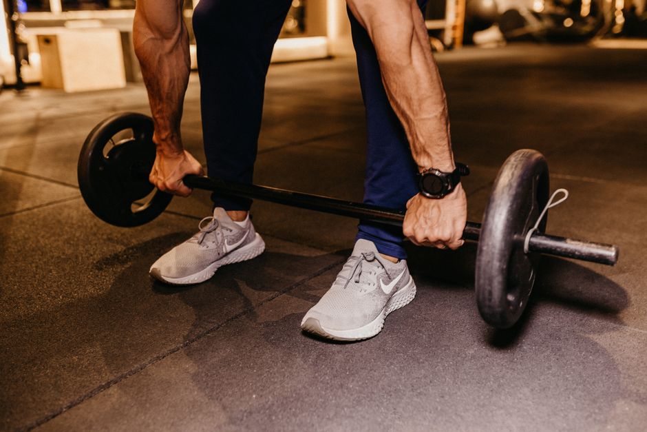 Um homem muscular com músculos definidos segurando um troféu e com um sorriso de vitória