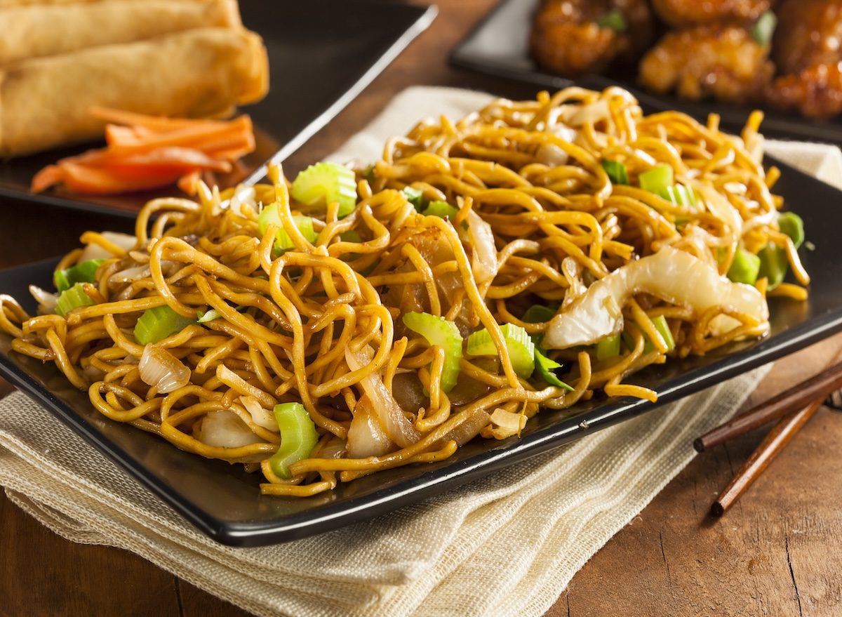 Uma tigela de lo mein congelado pronto, com vegetais congelados e um prato de arroz ao lado
