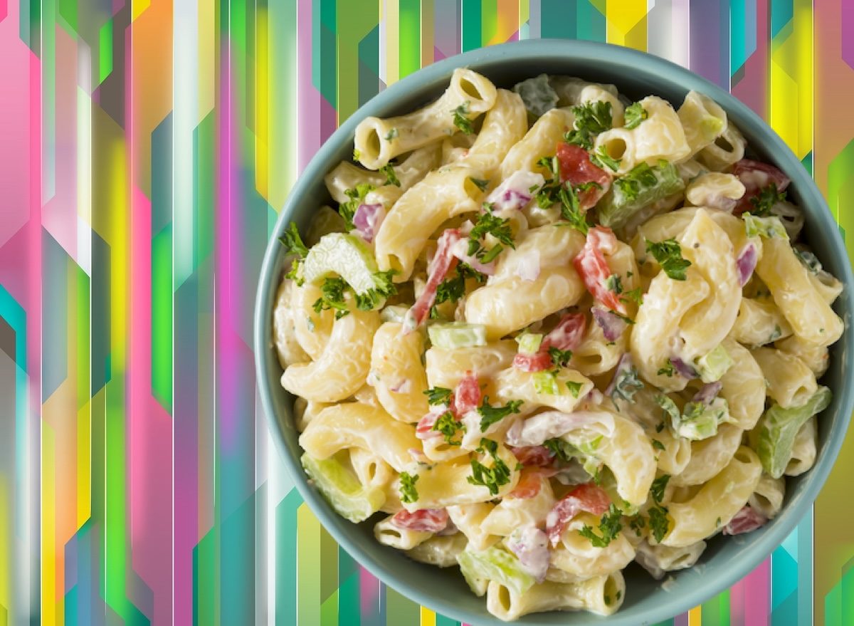 Macarrão cozido em uma tigela ao lado de legumes frescos e queijos amarelos