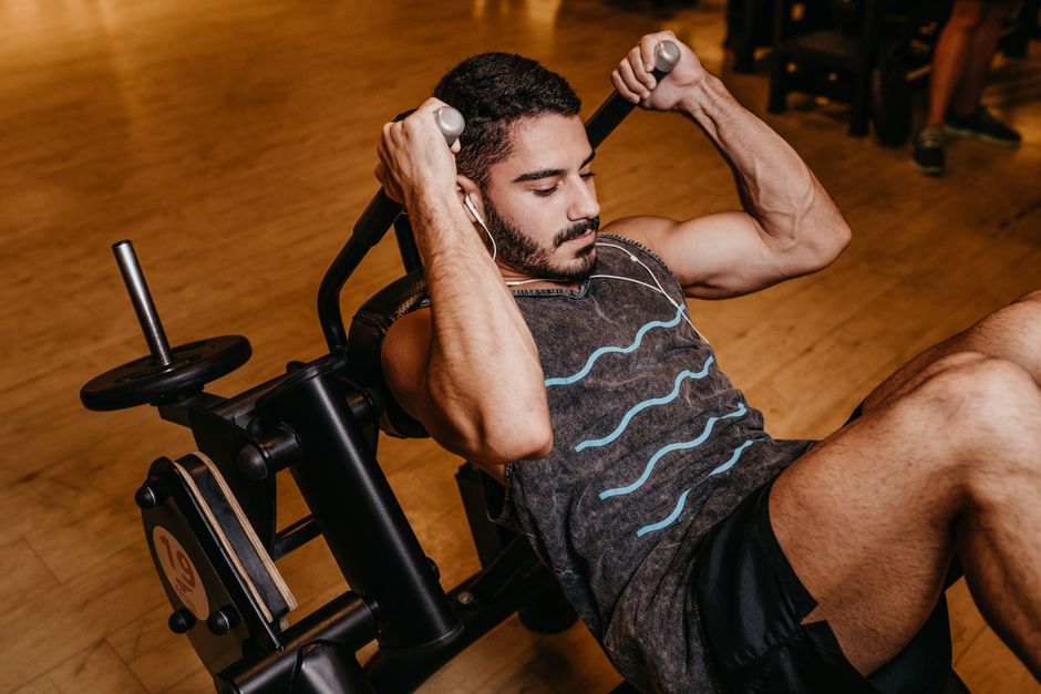Mulher em roupa esportiva encostada na parede fazendo marcha de pé, ao lado de um prato de salada e garrafa d'água