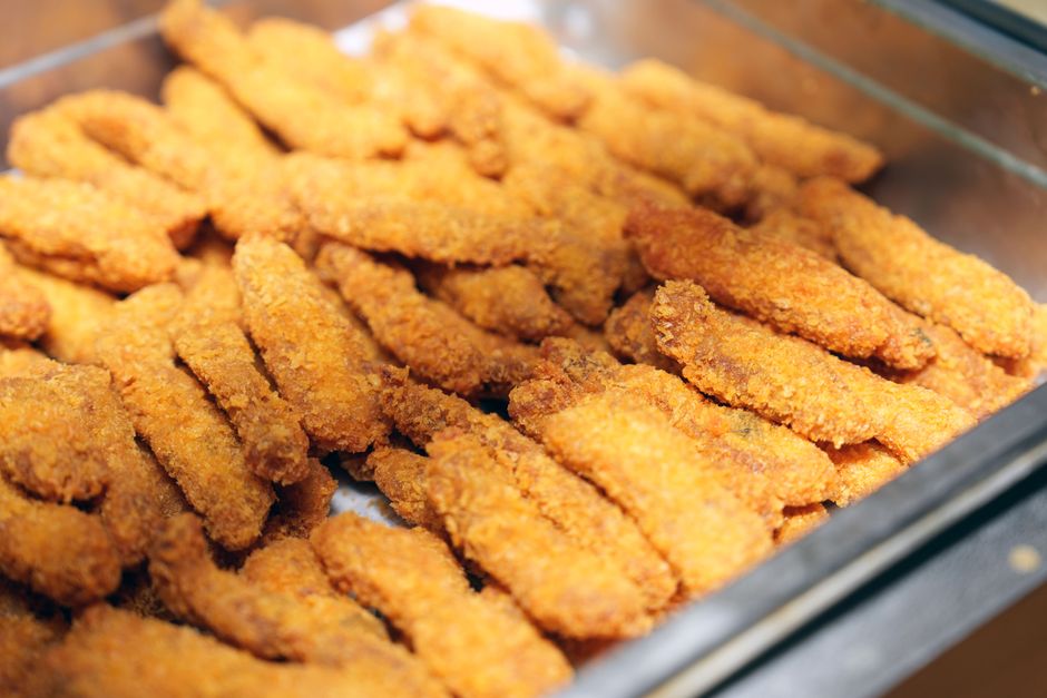 Um prato de peixe frito crocante, com fatias de limão e folhas de alface