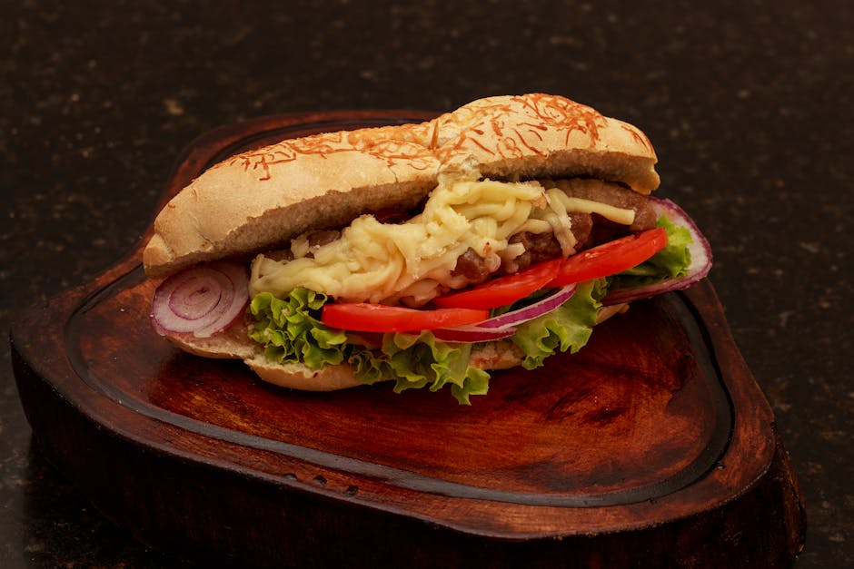 Sanduíche de peixe grelhado em pão integral com alface fresca e rodelas de tomate em um prato de madeira
