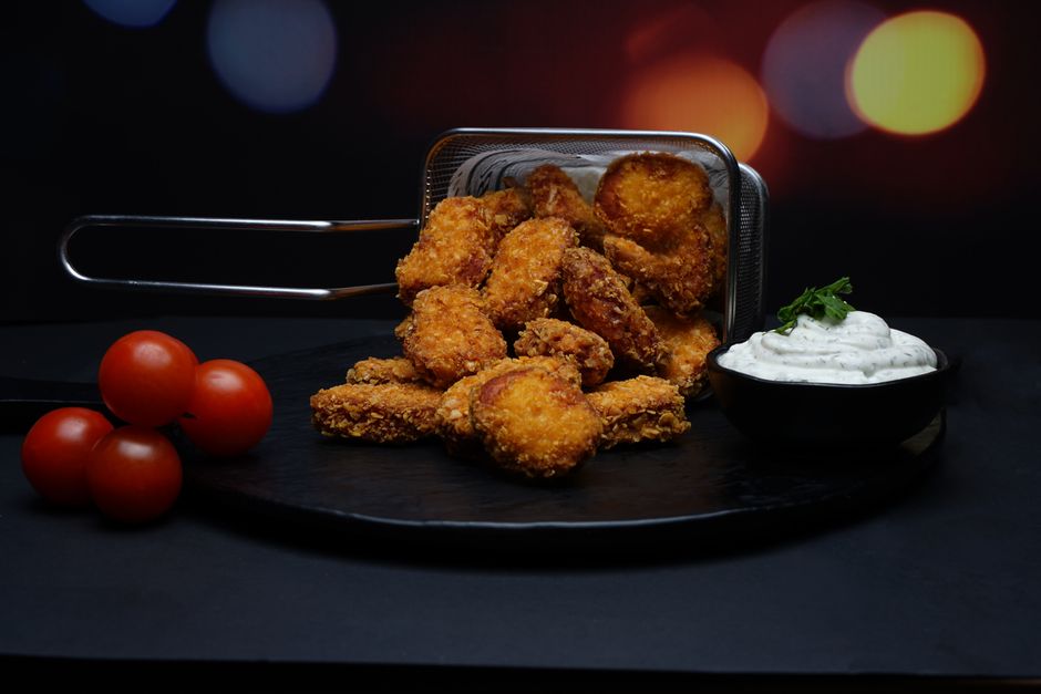 Potato skins crocantes congelados ao lado de um shaker de whey, halteres e uma maçã verde sobre um balcão