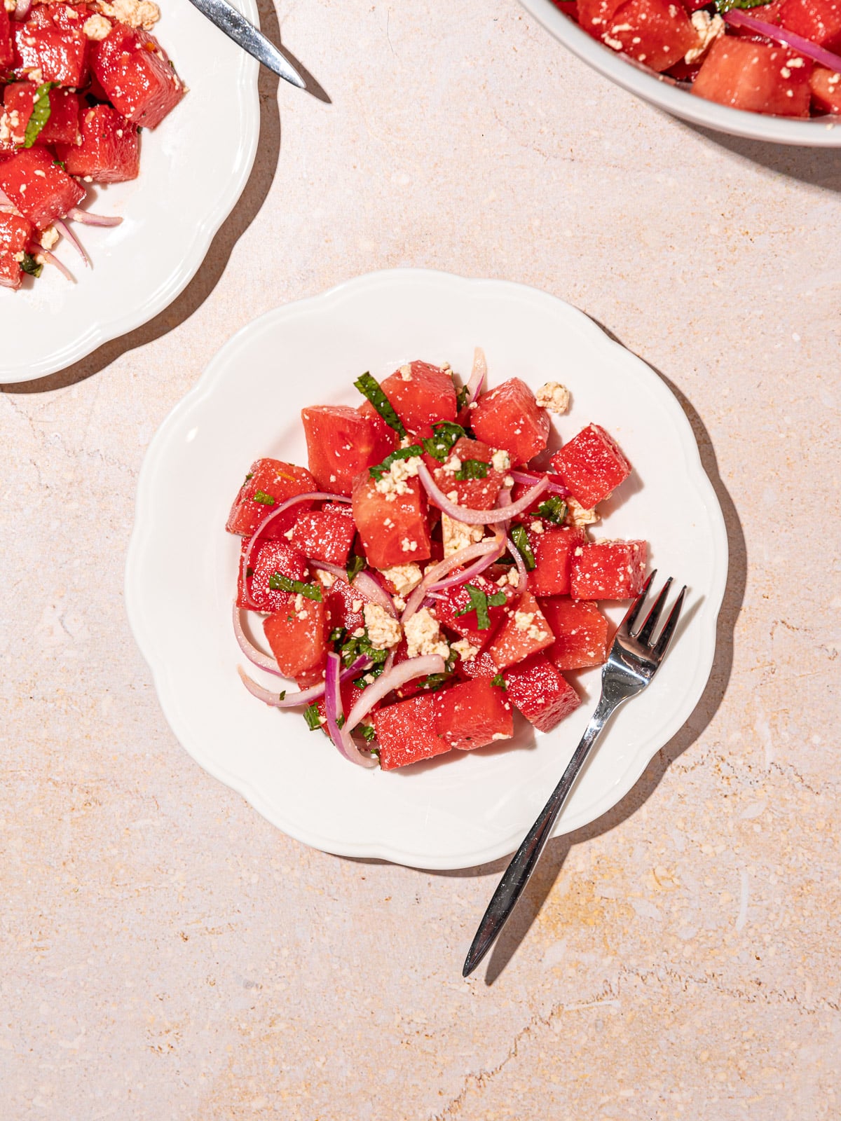 Uma melancia cortada em cubos e feta vegano picado sobre uma toalha de mesa branca