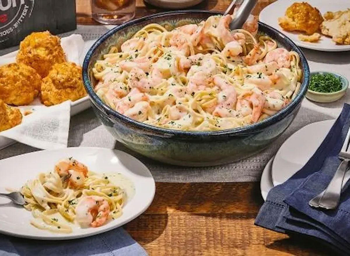 Um prato de seafood alfredo com frutos do mar frescos, como camarões e lagostas, sobre uma massa al dente e coberto por um molho cremoso branco