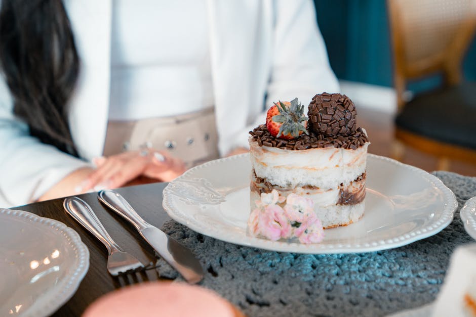 Uma colher de sobremesa repousa sobre um prato com mousse de chocolate, frutas vermelhas frescas e calda brilhante