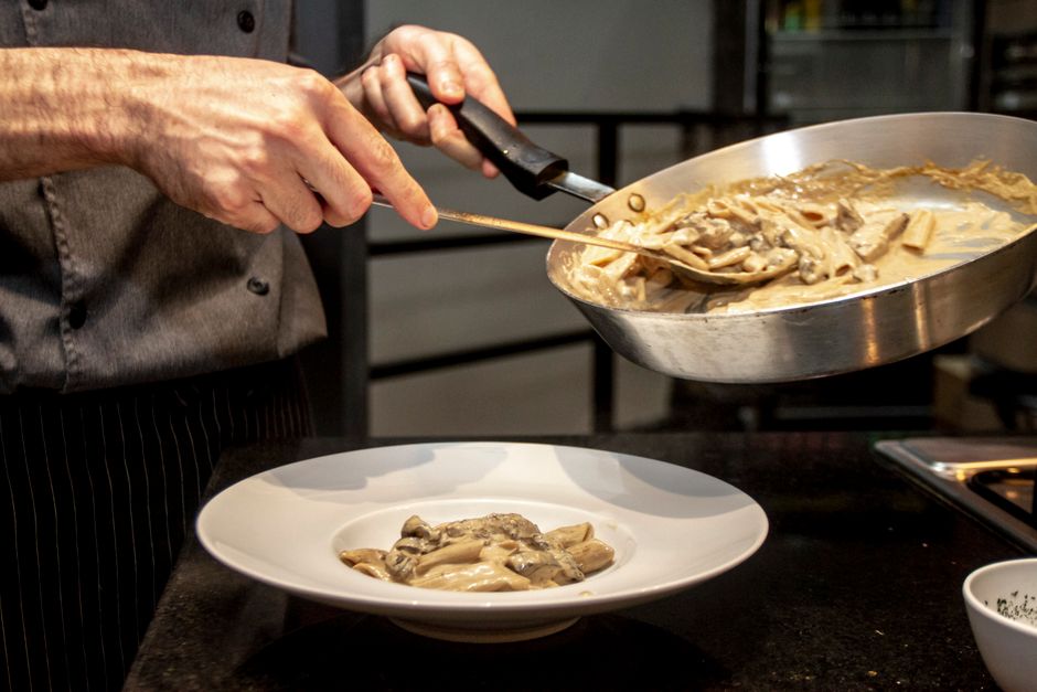 Prato de spaghetti ao forno com molho vermelho, queijo derretido e legumes verdes ao lado, sugerindo refeição equilibrada