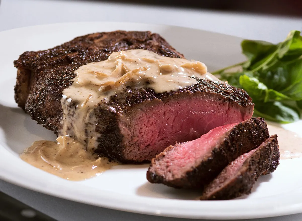 Um steak de 300g a 400g acompanhado por vegetais e arroz, servido em uma mesa simples