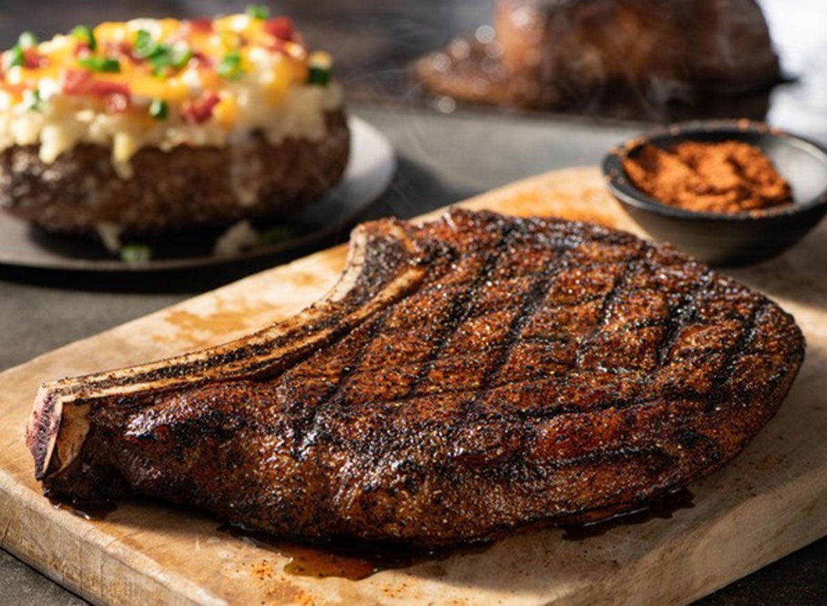 Um steak de carne vermelha grelhado ao lado de batatas assadas crocantes e saladas frescas