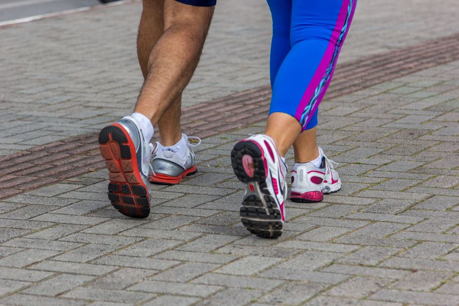 Mulher em exercício de step-ups em uma plataforma de madeira com rodas de exercícios ao fundo