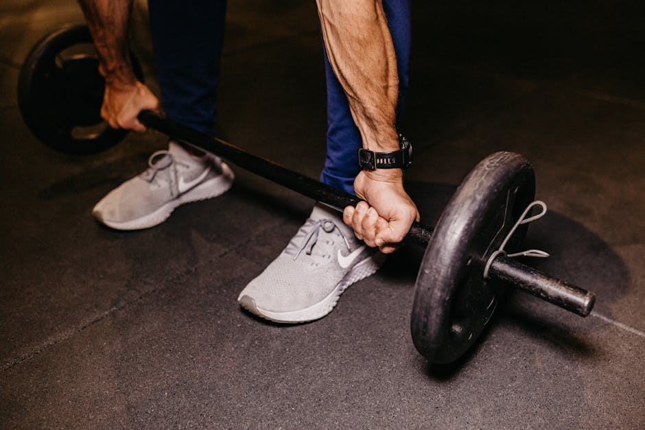 Pessoa com mais de 55 anos realizando elevação lateral com halteres em uma academia iluminada e bem equipada