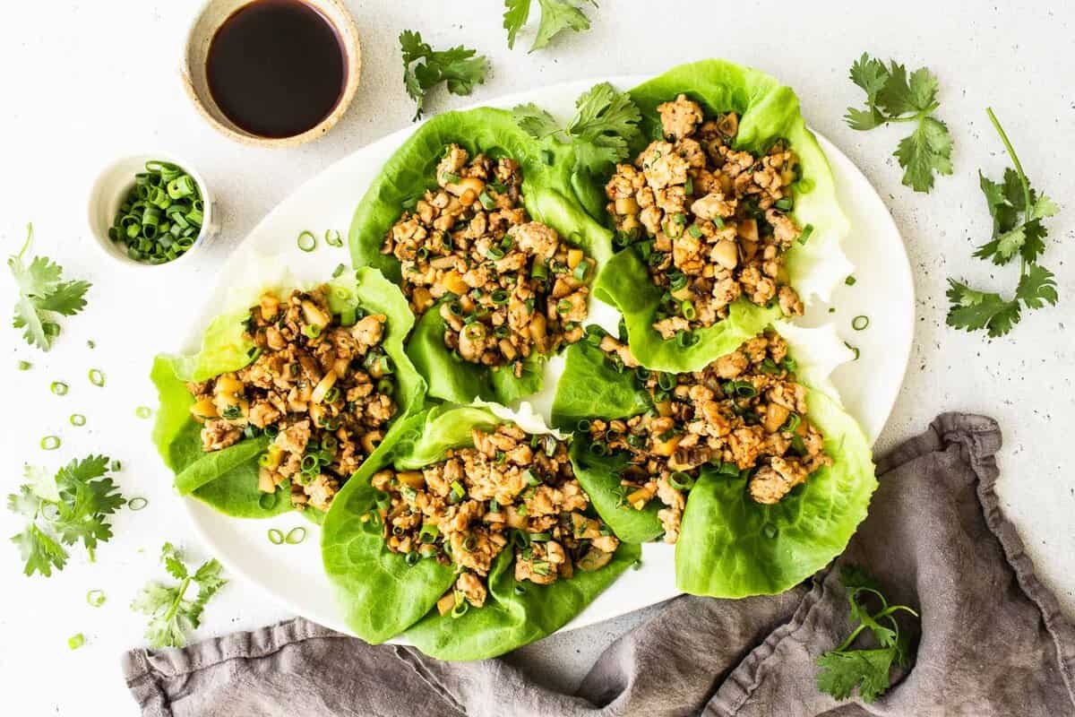 Um prato de wraps de alface com frango grelhado e molho de azeite e limão sobre uma mesa de madeira